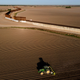 The border wall construction is seen near farmland as a tractor plows a field in Progreso, Texas
